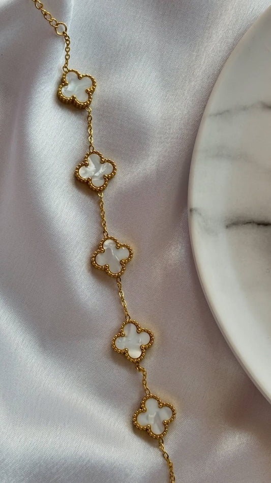 Gold necklace with clover-shaped pendants on a white fabric background
